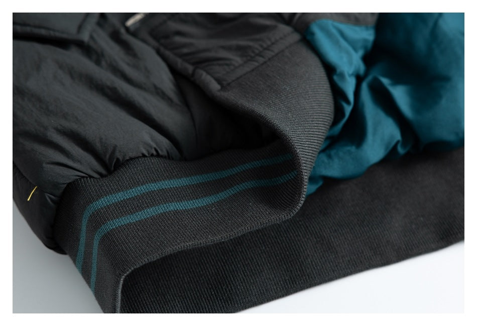 Close-up of a charcoal ribbed garment hem with teal stripes beside gathered dark fabric.