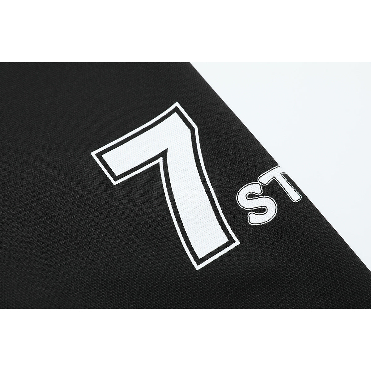 Close-up of black sleeve fabric with a large white outlined number 7 and smaller lettering.
