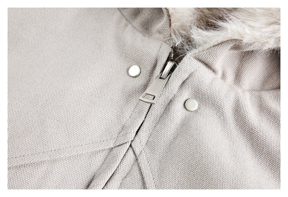 Close-up of a beige jacket showing its zipper, two snap fasteners, textured fabric, and hood lining.