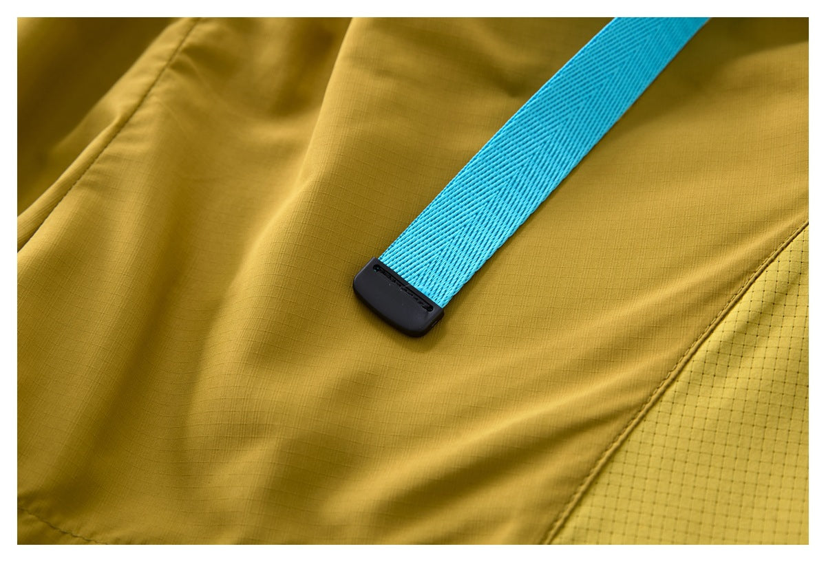 Close-up of a bright blue belt end and black adjuster against the mustard shorts and perforated side panel.