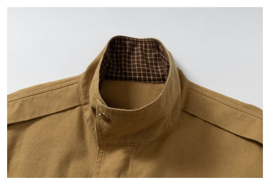 Close-up of the jacket’s raised collar, checked inner collar lining, shoulder tabs, and button closure.