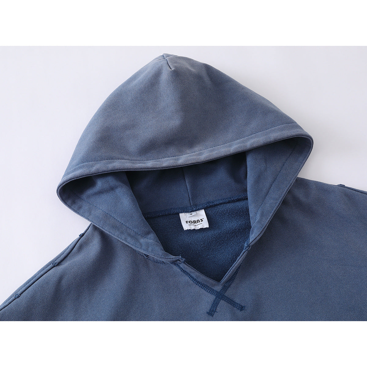 Close-up of a slate-blue hoodie showing its lined hood, crossed neckline stitching, and small neck label.