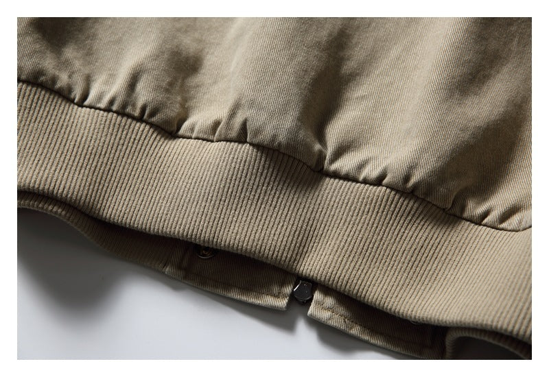 Close-up of the taupe jacket's ribbed hem, gathered fabric and lower snap closure.