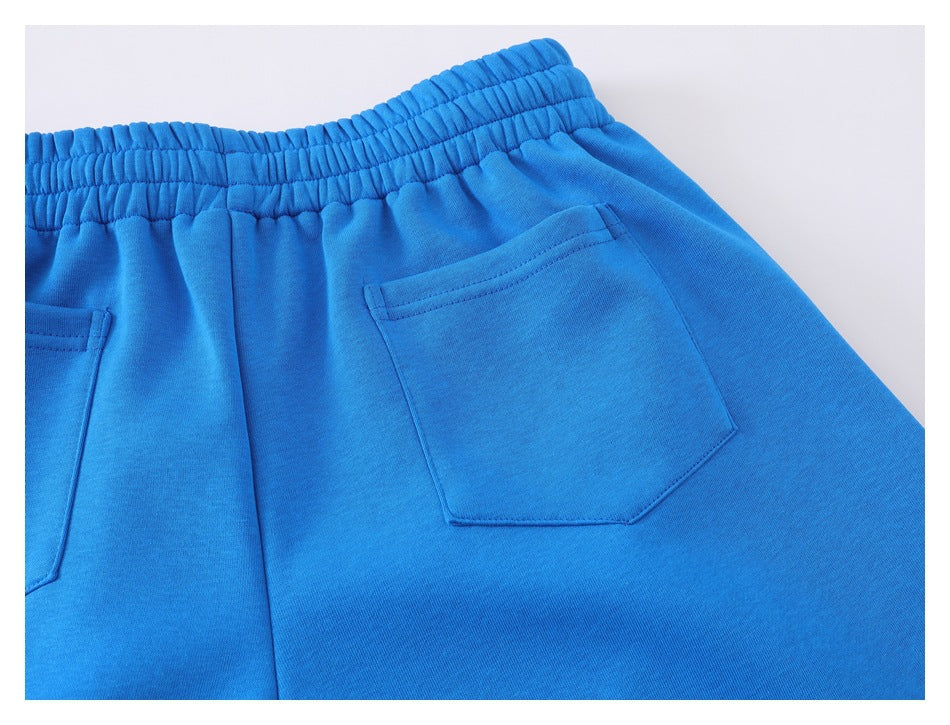 Close-up of the back of bright blue pants, showing an elastic waistband and two patch pockets.