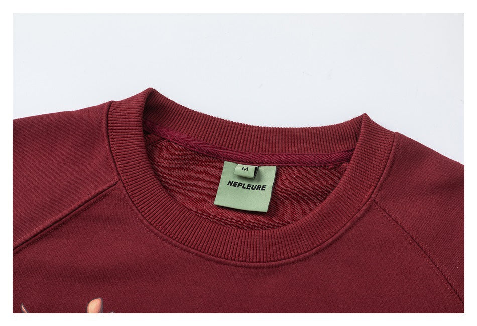Close-up of a burgundy sweatshirt crew neck with ribbed collar and sewn NEPLEURE label.