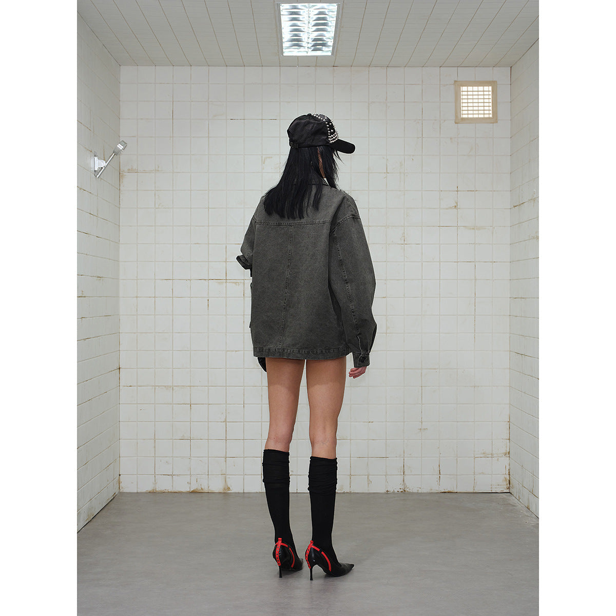 Model wearing an oversized charcoal gray jacket, shown from the back.