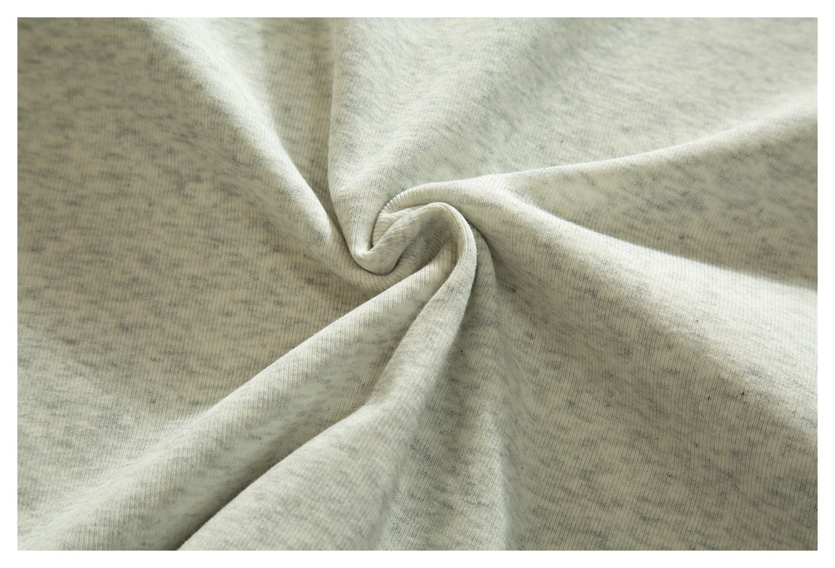 Close-up of pale heather gray fabric gathered into a twist, showing its mottled texture.