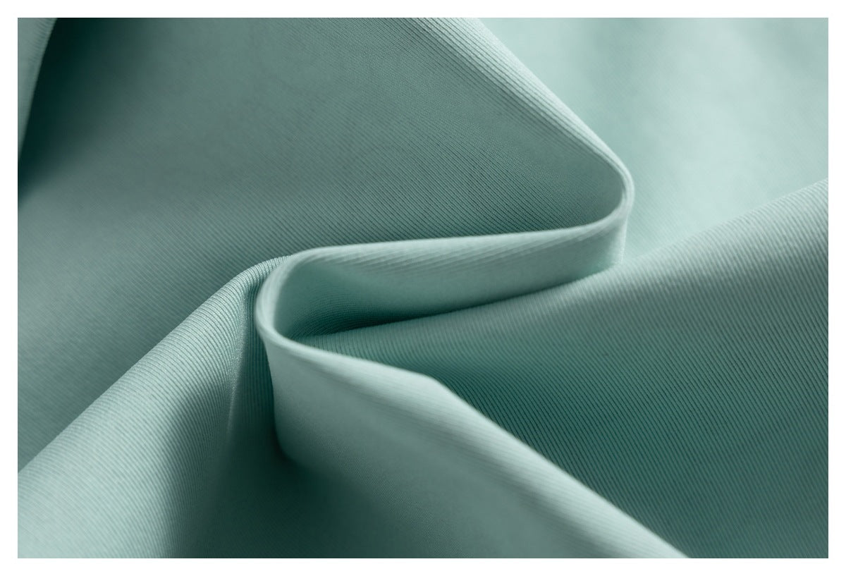 Close-up of pale sage green fabric with fine diagonal ribbing and soft folds.