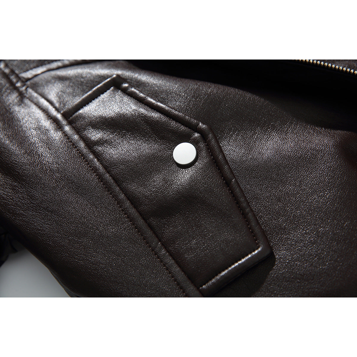 Close-up of a dark brown jacket pocket flap with a round snap and a nearby zipper.