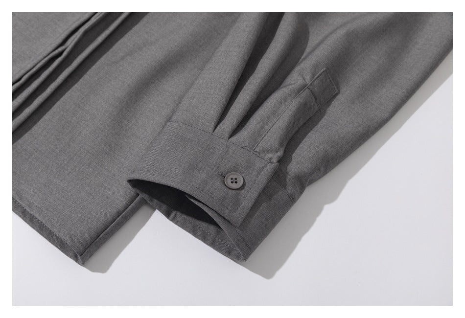 Close-up of a gray shirt sleeve cuff with a button and stitched pleats.