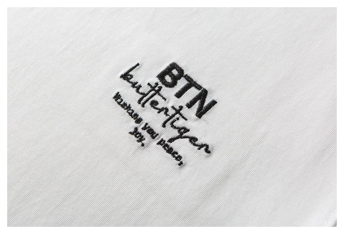 Close-up of black embroidered lettering on white T-shirt fabric.