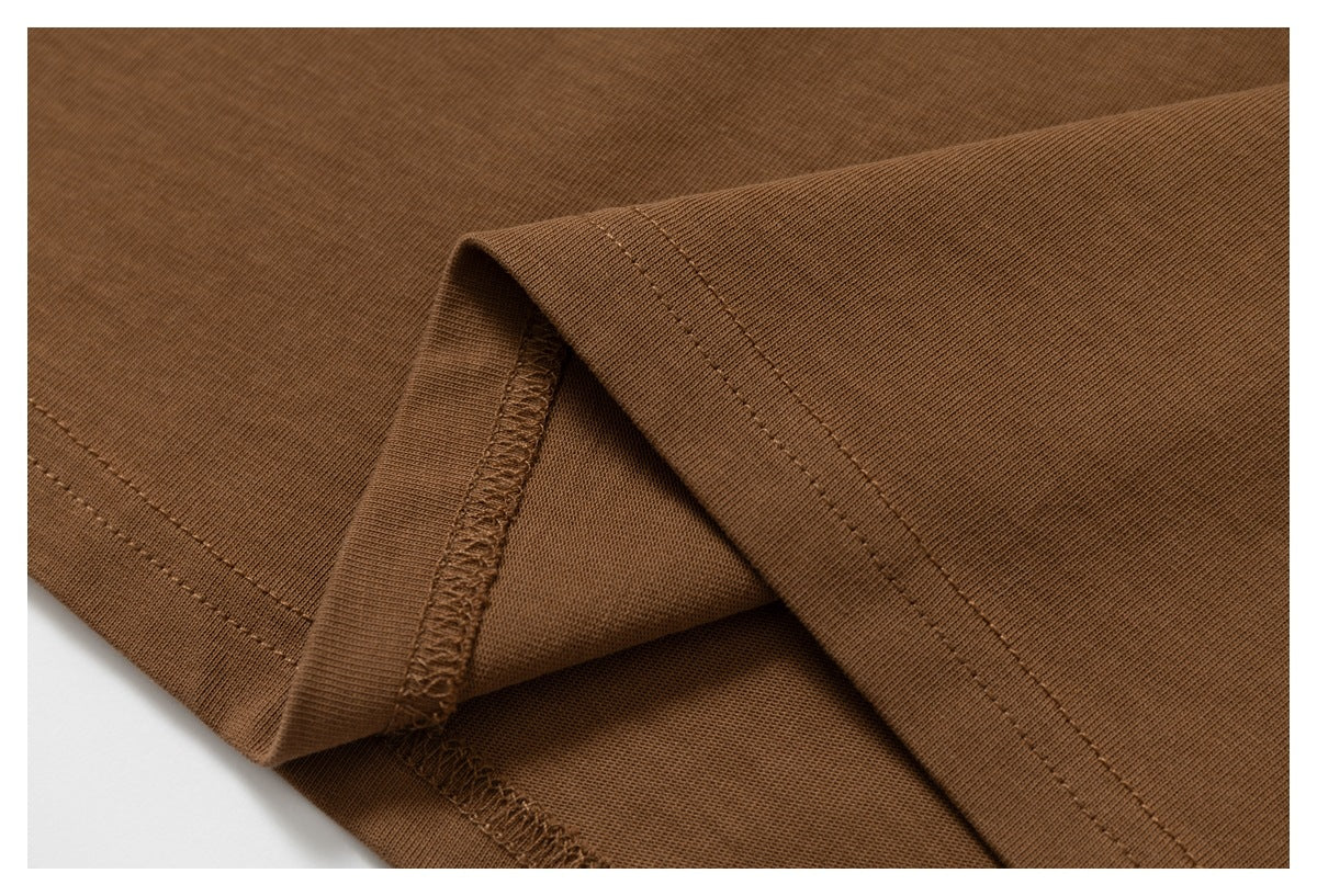 Close-up of a brown garment's folded edge, showing stitching and an overlocked seam.