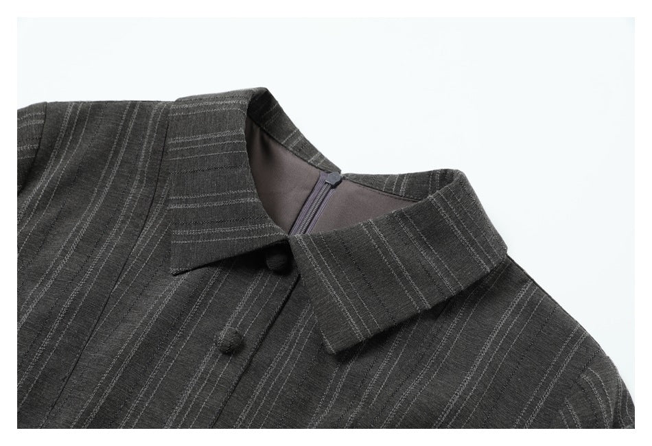 Close-up of the upper front of a charcoal pinstriped garment, showing its pointed collar and buttons.