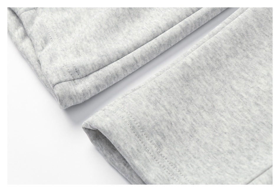 Close-up of a stitched hem on light gray heathered sweatpants.