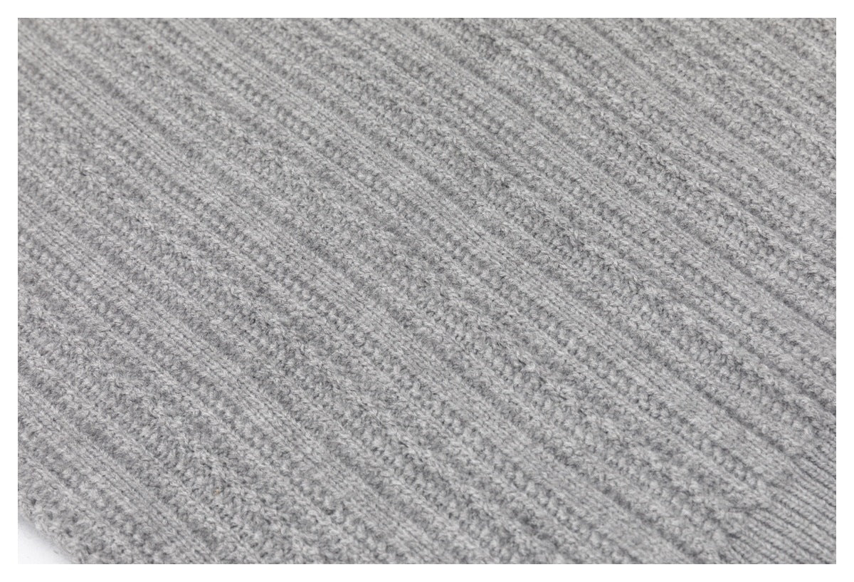 Close-up showing the textured light gray knit and diagonal rib pattern of a garment.