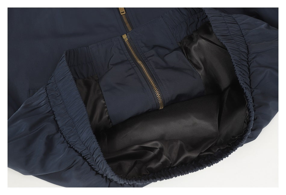 The dark jacket is opened to show its black lining, gold zipper, and gathered waistband.