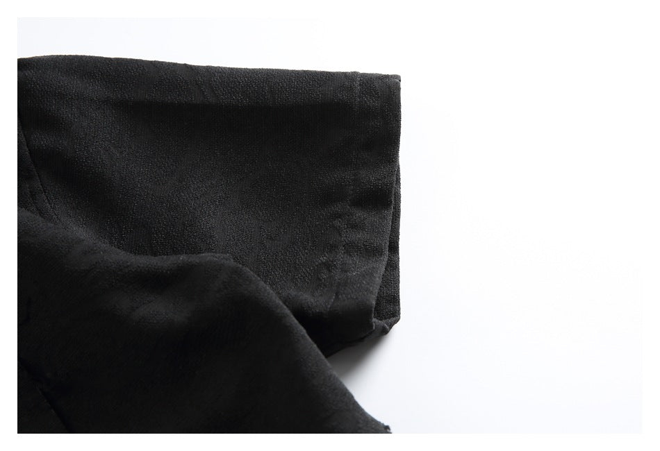Close-up of the black shirt sleeve and cuff against a white background.