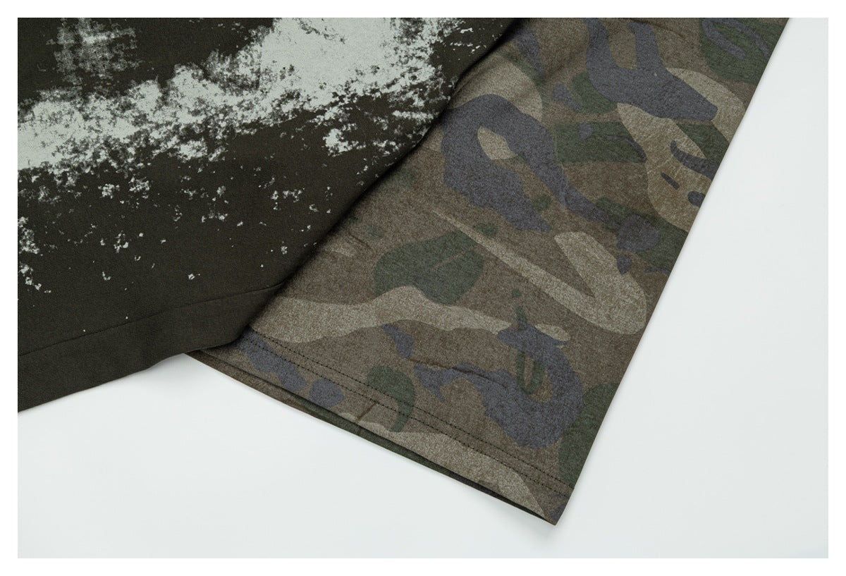 Close-up of the T-shirt's camouflage sleeve and hem beside the distressed graphic on its dark olive body.