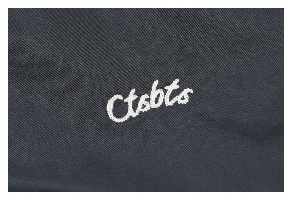 White cursive embroidery on dark charcoal fabric.