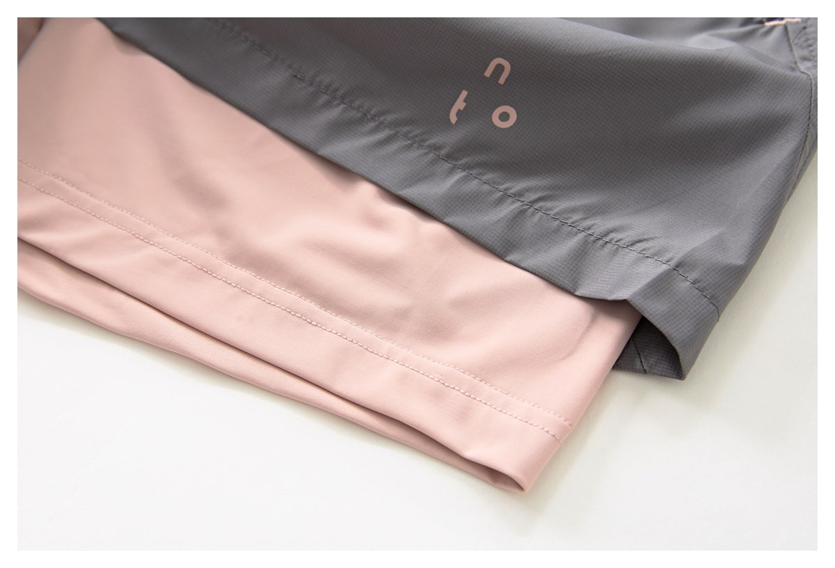 Close-up of gray and pale pink garment panels with stitched hems and partial lettering on the gray panel.
