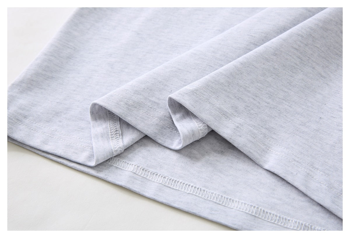 Close-up showing the double-stitched hem and overlocked seam of a light gray T-shirt.
