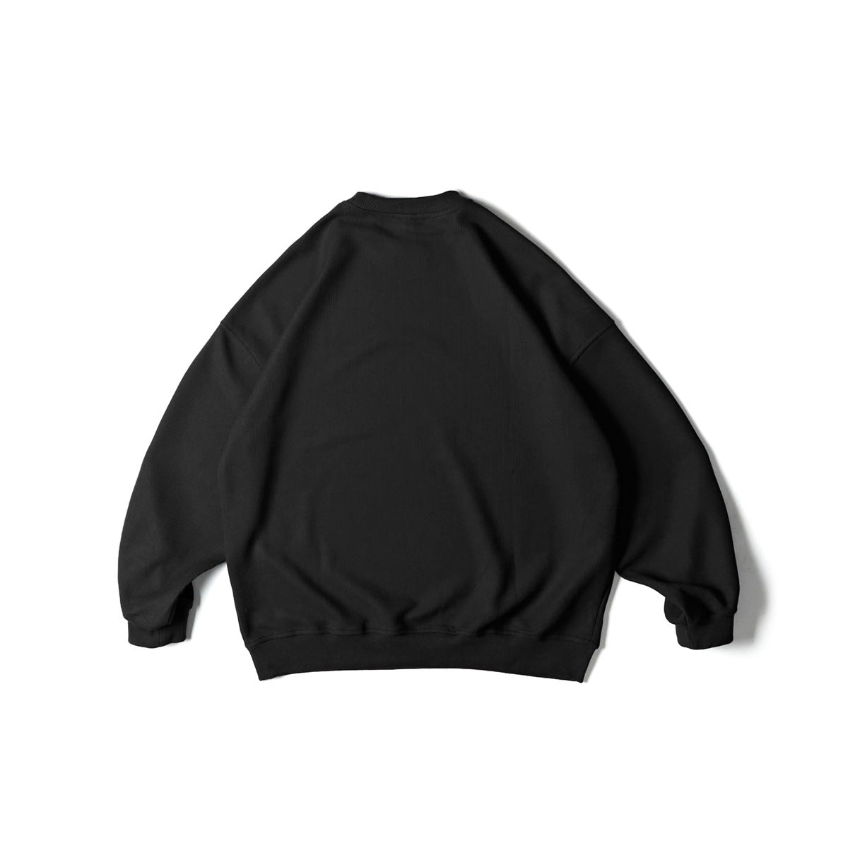 Back view of a black textured crewneck sweatshirt with dropped shoulders and ribbed cuffs and hem.
