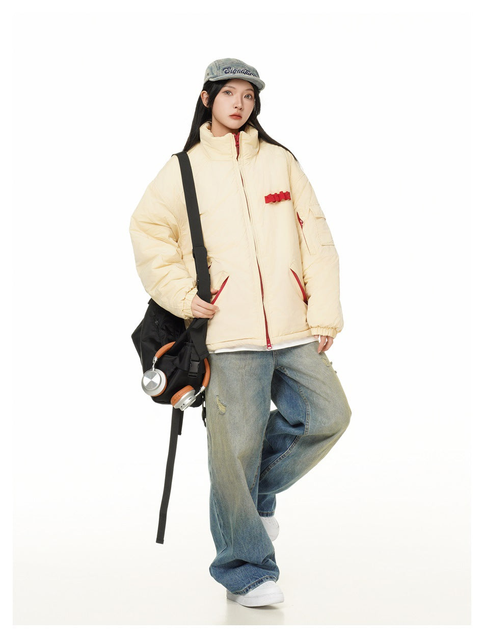 Model wearing beige puffer jacket with red zipper details, wide-leg jeans, cap and black shoulder bag
