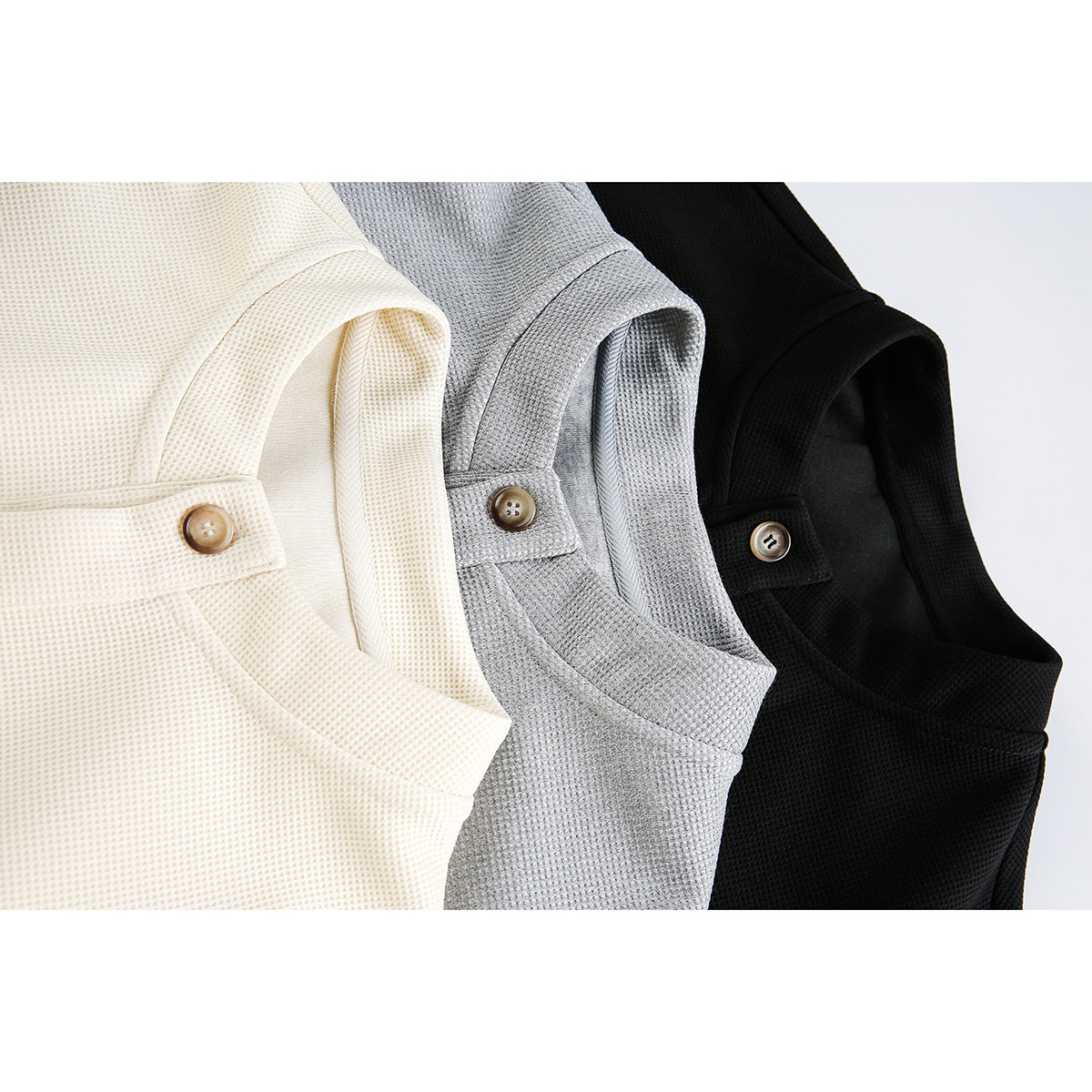 Close-up of cream, gray, and black button-front jackets showing their textured fabric and collar fastenings.
