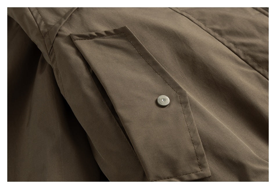Close-up of a brown jacket pocket flap fastened with a small metal snap.