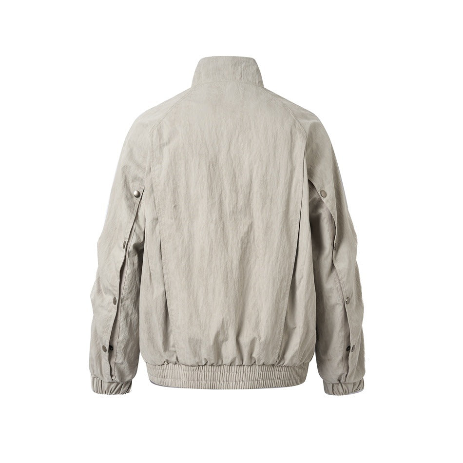Back view of a light gray-beige jacket with a stand collar, gathered hem, and snap details on the sleeves.