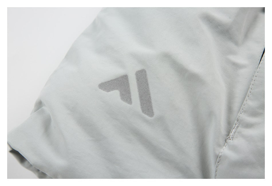 Close-up of a small gray emblem printed on a light gray garment beside a stitched seam.