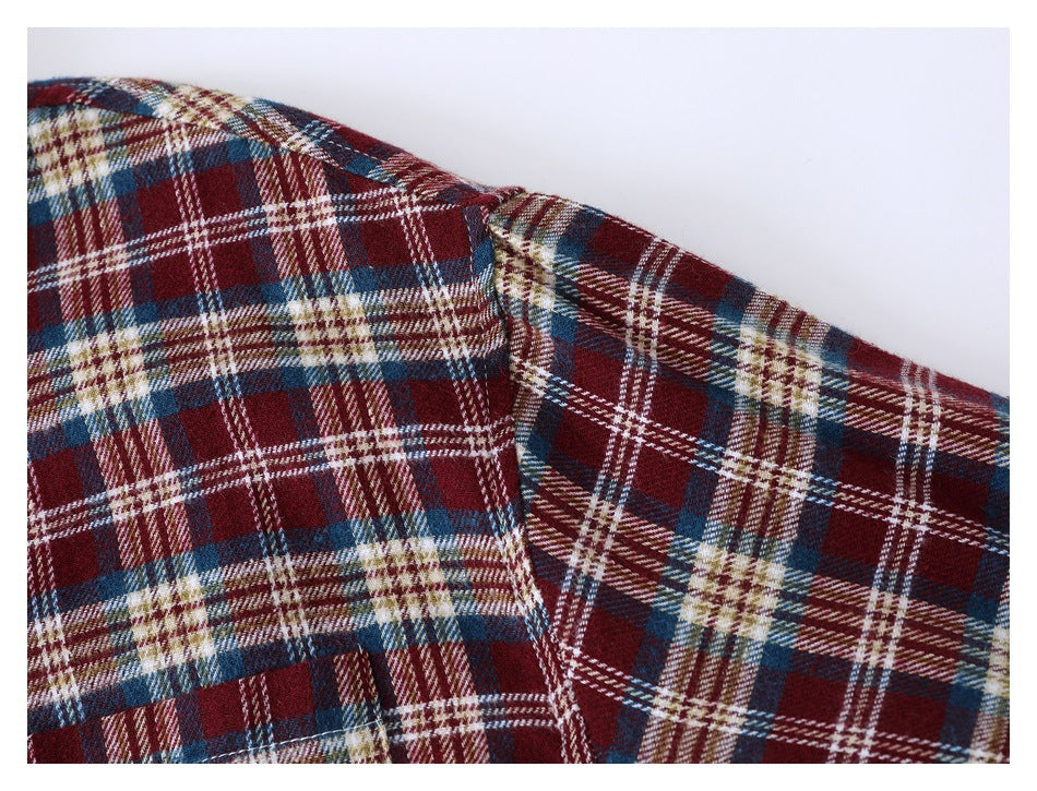 Close-up of a burgundy, navy, cream, and tan plaid shirt showing the shoulder seam.