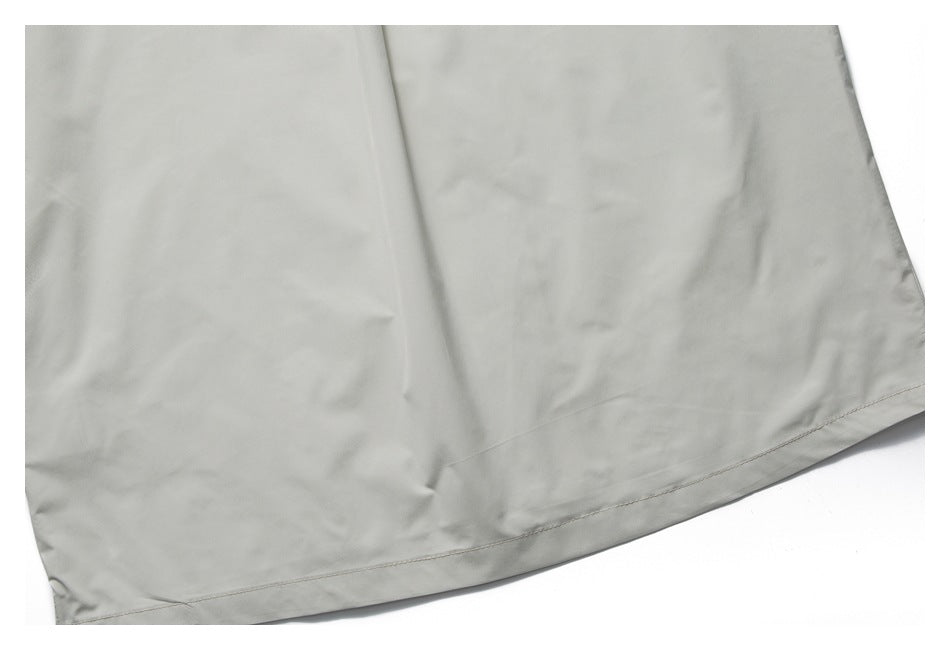 Close-up of the plain pale gray shirt body and curved stitched lower hem.