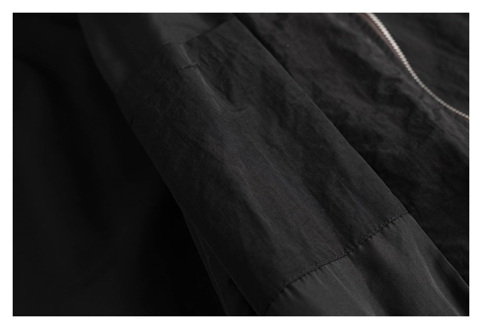 Close-up of a black jacket sleeve showing its panel seam and stitching.