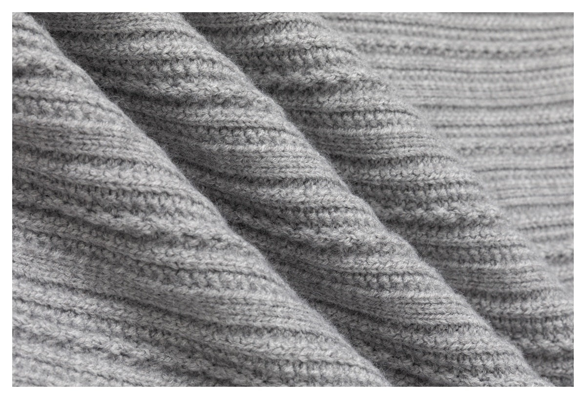 Macro view of the light gray garment's raised ribbed knit texture.