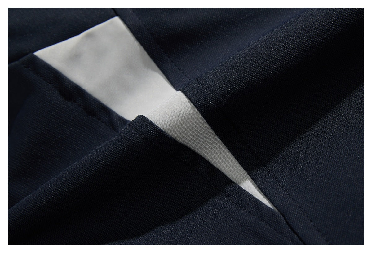 Close-up of dark navy garment fabric folded back to reveal a pale inner panel and stitched seam.