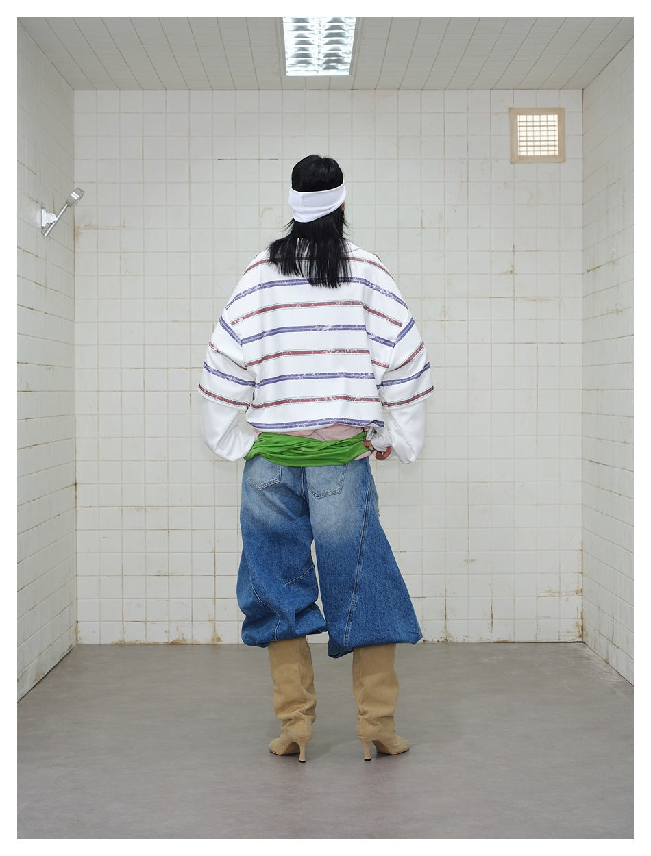 Back view of model wearing the white top with navy and burgundy horizontal stripes, styled with jeans and tan boots