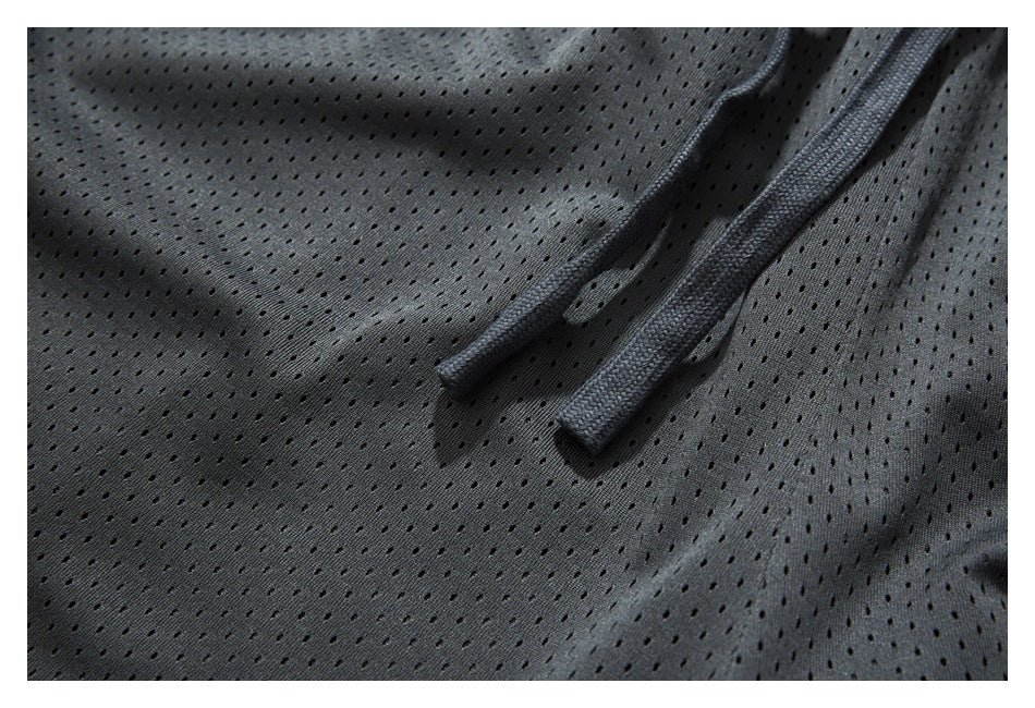 Close-up of charcoal perforated shorts showing the matching drawstring ends and fabric eyelets.