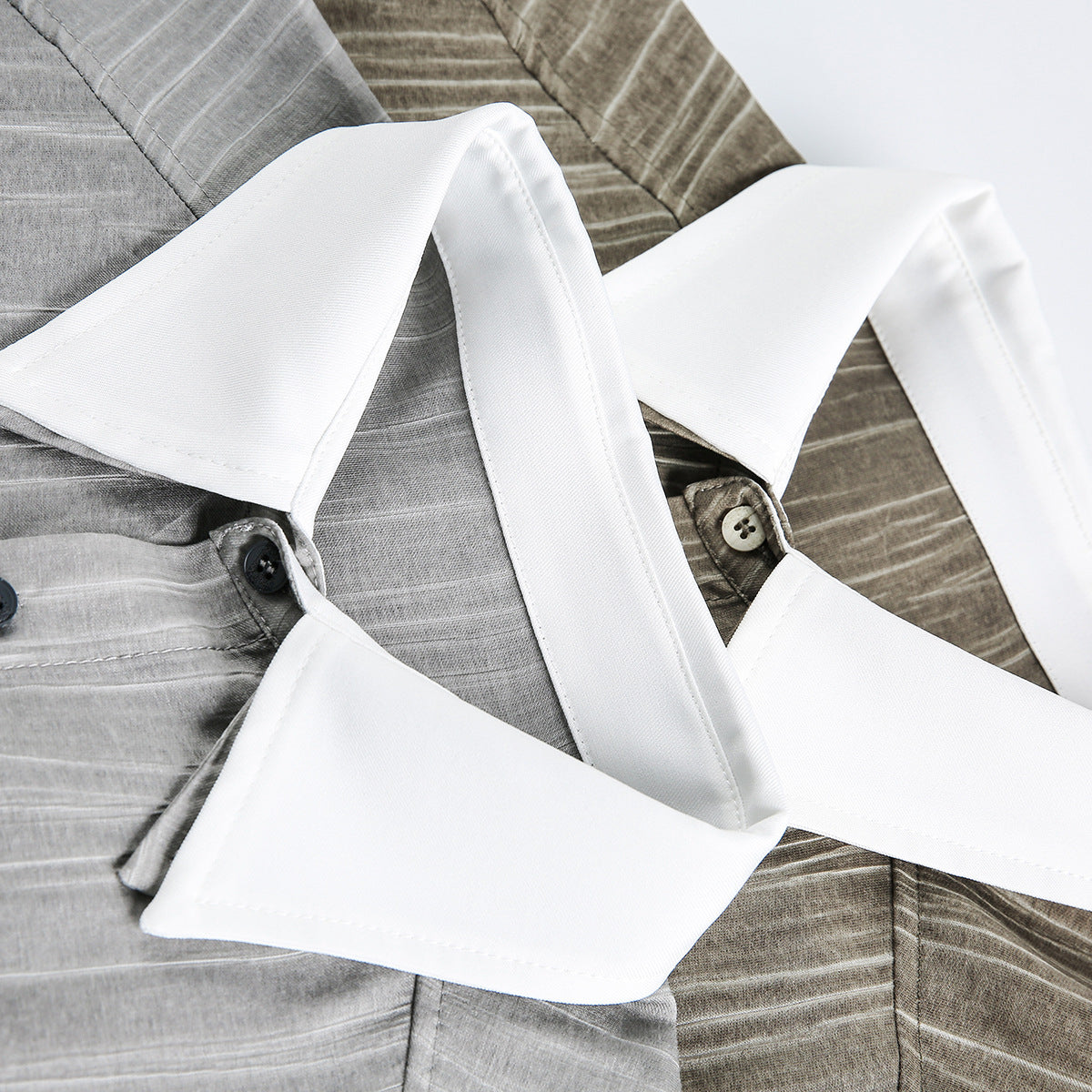 Close-up of two gray striped shirts with contrasting white collars and dark buttons.