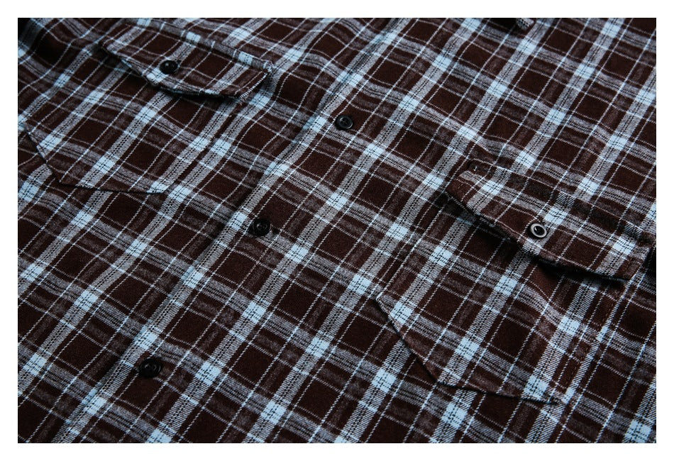 Front of a flat-laid dark brown plaid button-up shirt with two buttoned chest pockets.
