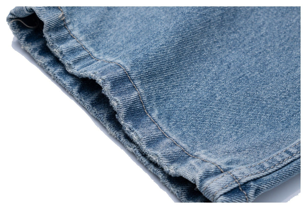Close-up of the jeans leg hem with visible stitching and a slightly frayed edge.
