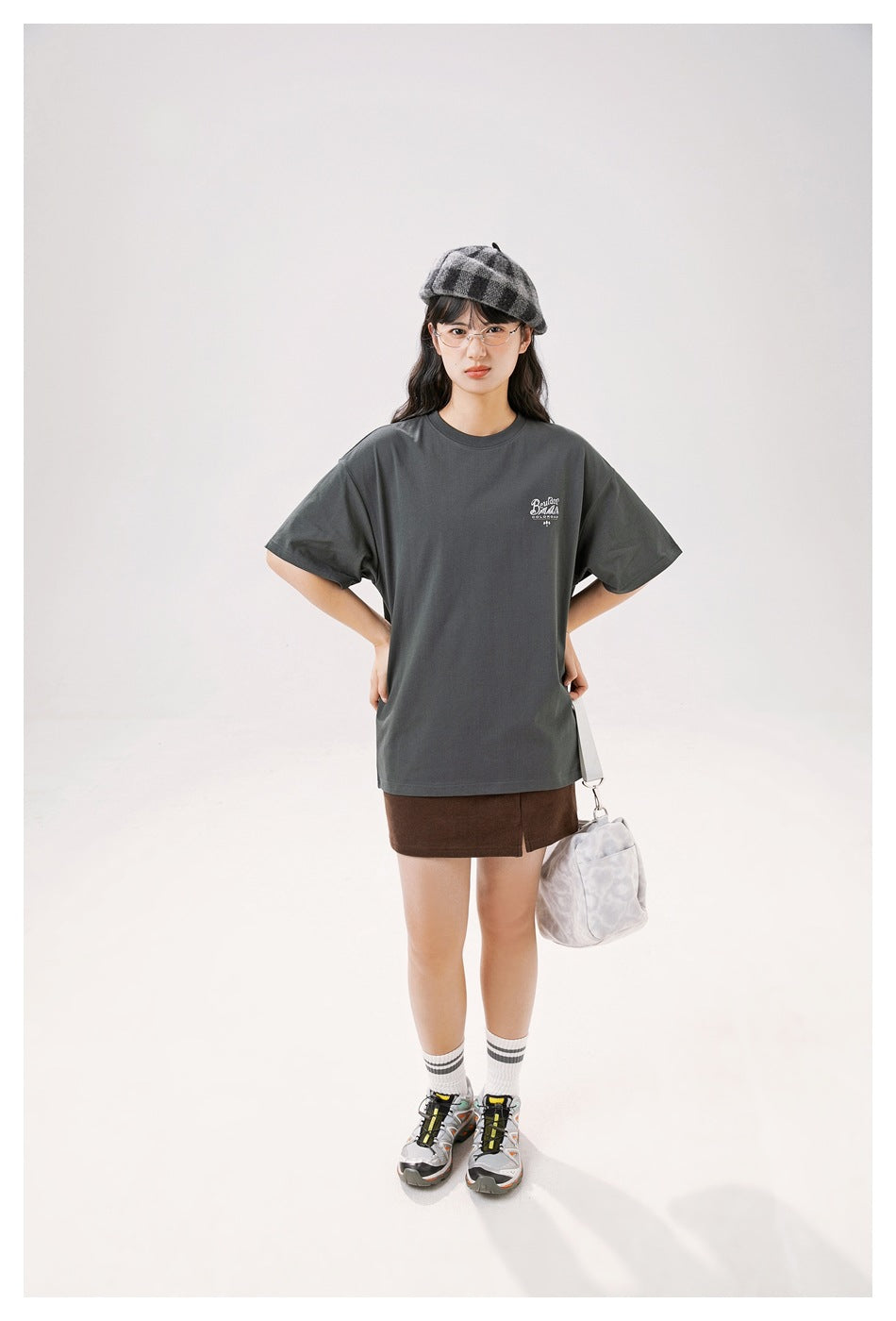 Full-length model wearing a charcoal gray oversized T-shirt with a small chest print and brown shorts.