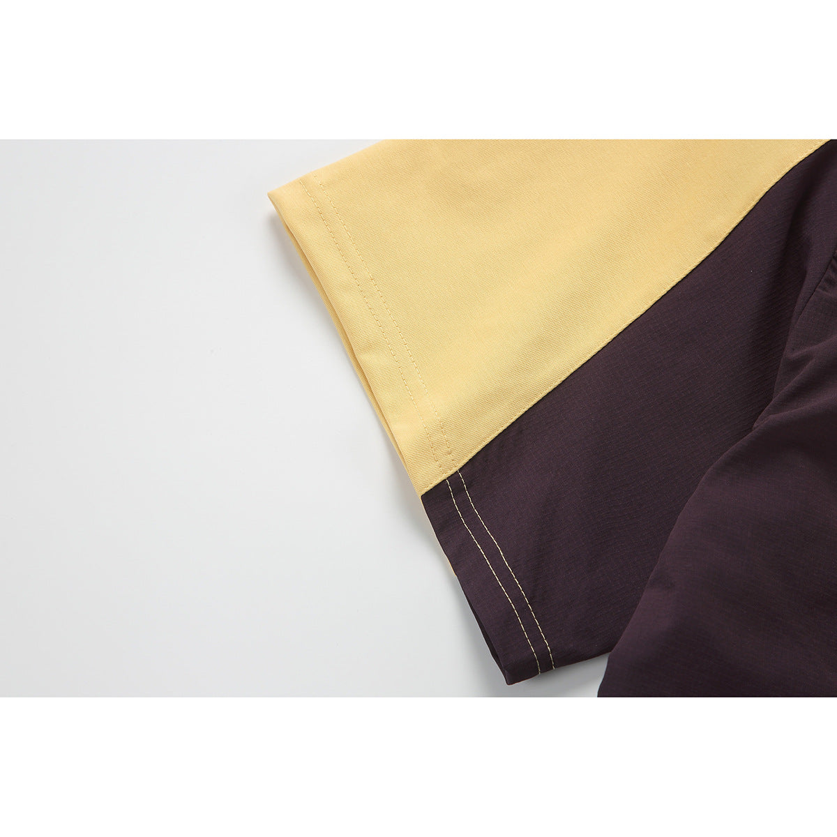 Close-up of yellow and dark color-block panels with contrasting seam stitching.
