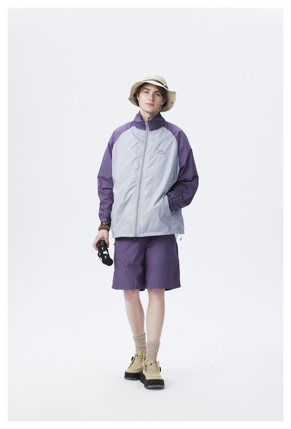 Full-length model wearing a light gray jacket with purple sleeves and matching shorts.