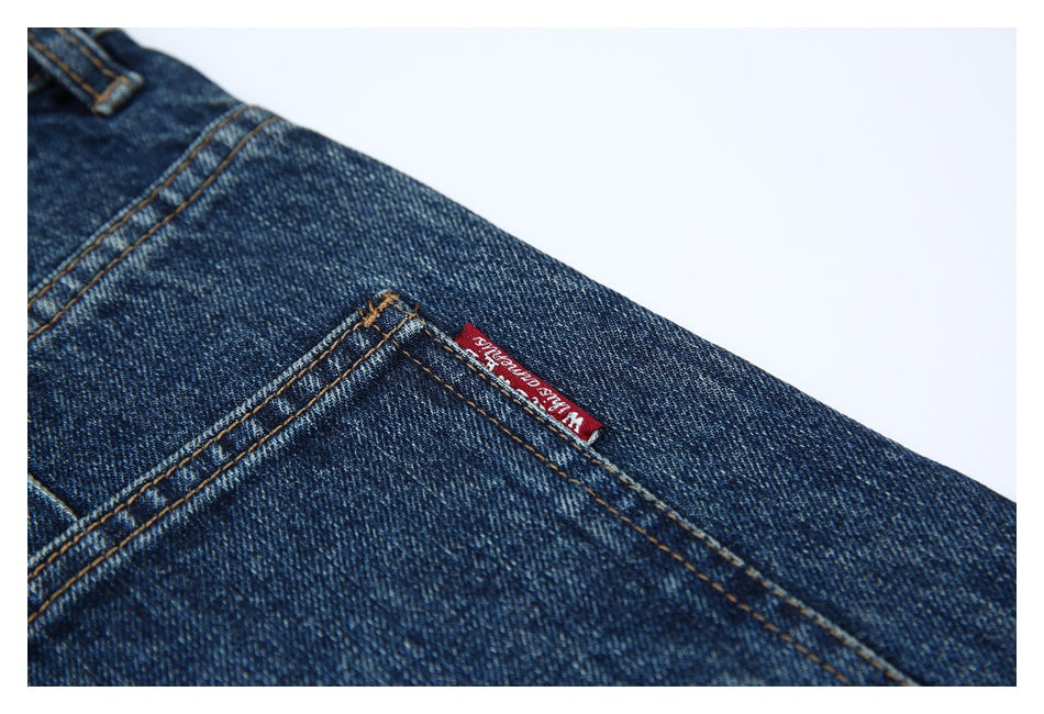 Close-up of dark indigo denim and back-pocket stitching with a small red woven label.