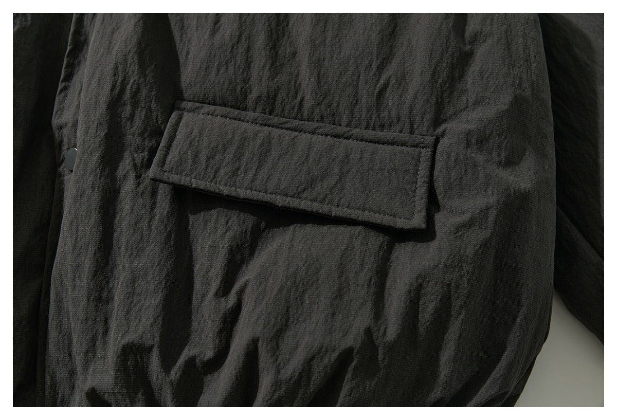 Close-up of a rectangular pocket flap on the charcoal jacket, shown unfastened.