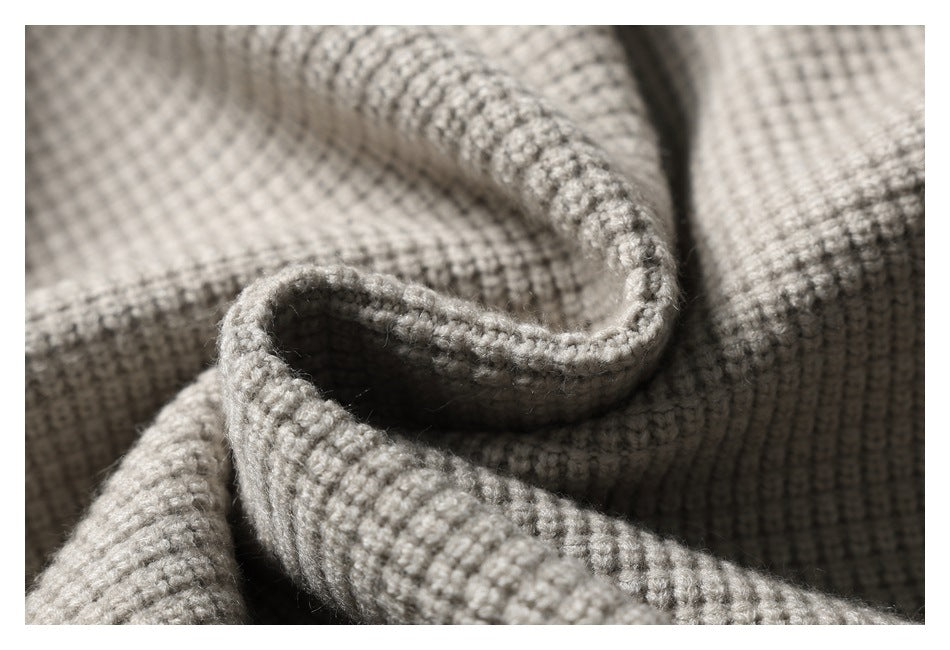 Close-up of softly textured taupe-gray fabric folded to show its raised edge and small grid-like knit pattern.