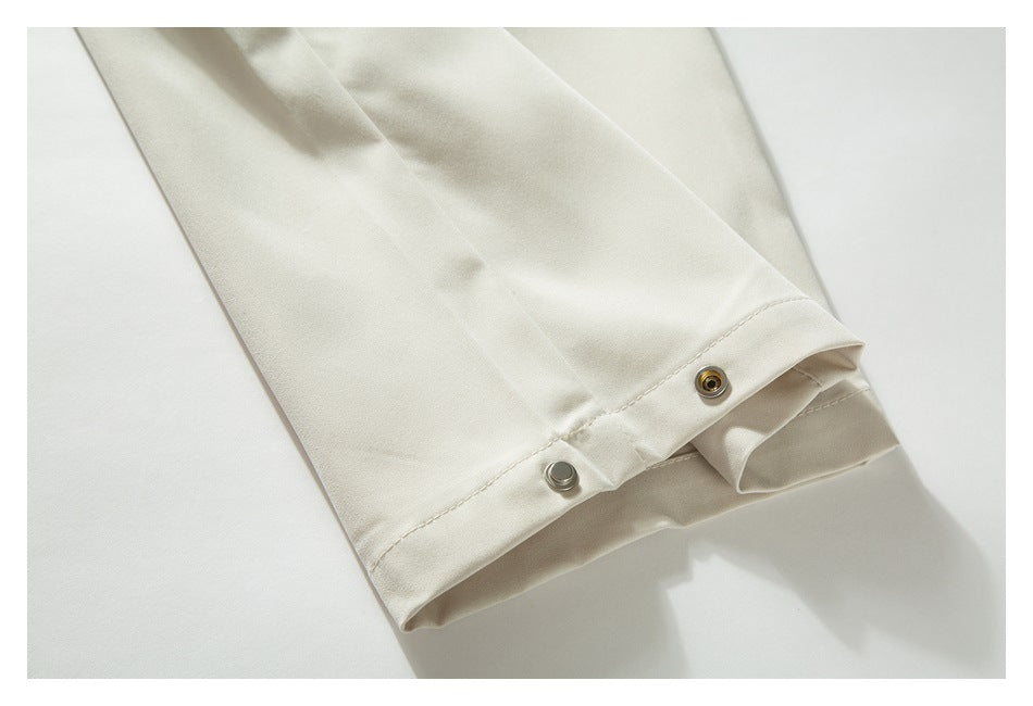 Close-up of the ivory pants hem with two metal snap fasteners.