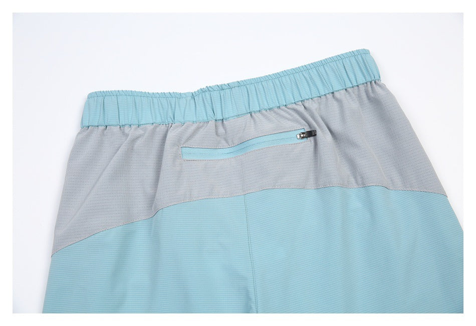 Back view of light blue shorts with a gray upper panel, elastic waistband, and small zip pocket.