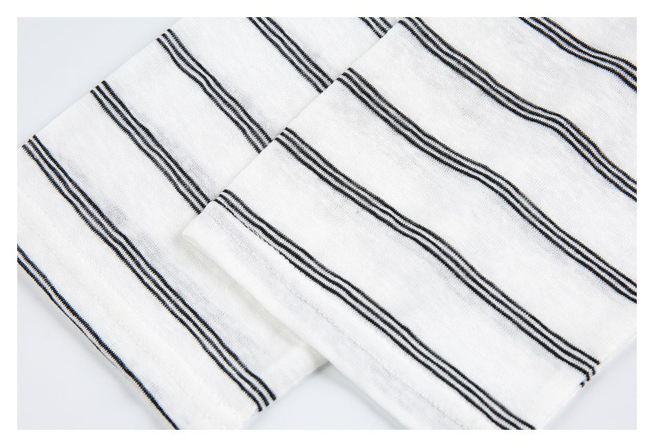 Close-up of layered white knit fabric with narrow black stripes and a folded edge.